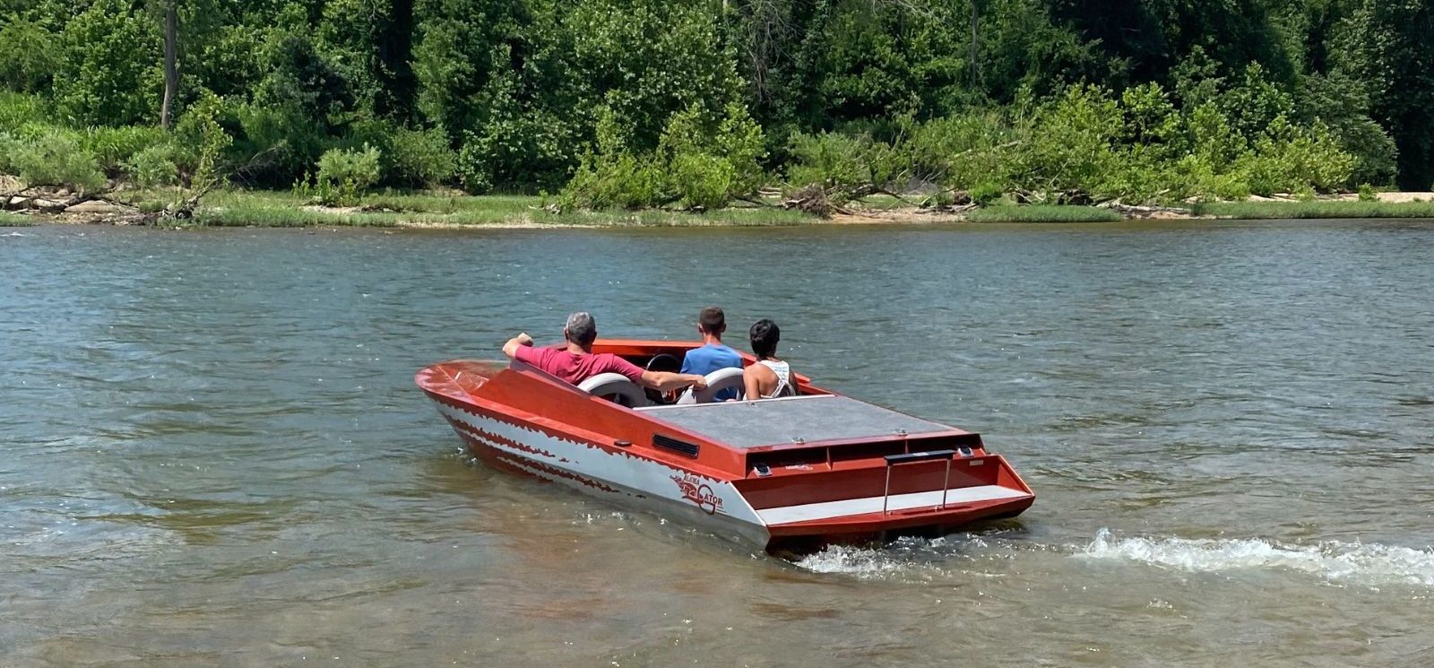 A picture of three people on a white and red boat.